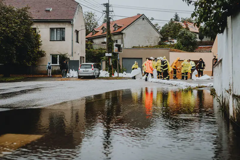 Emergency workers in rain gear managing floodwater on a residential street