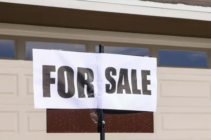 For Sale sign posted in front of a house with a garage