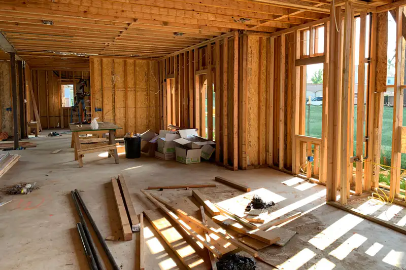 Sunlit house interior under construction with exposed wood wall framing