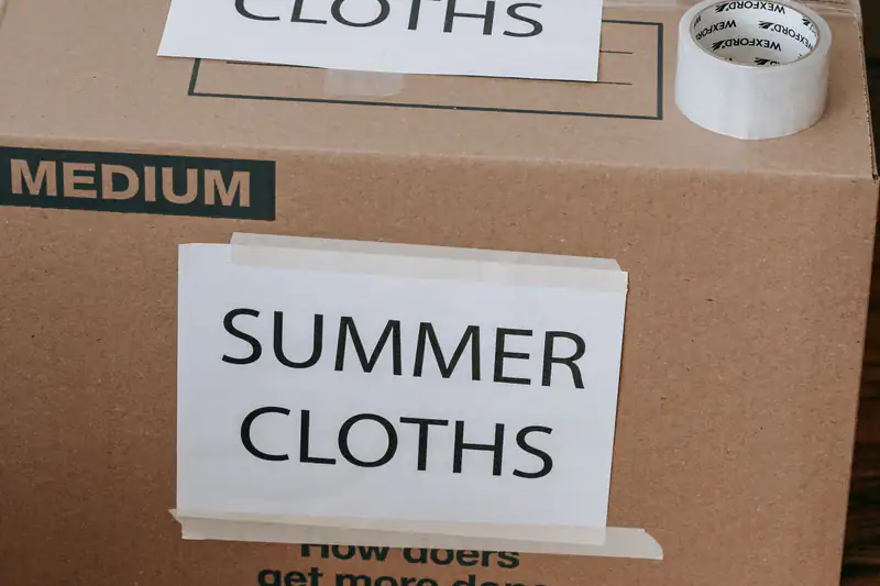 Cardboard storage boxes labeled for summer clothes, sealed with packing tape