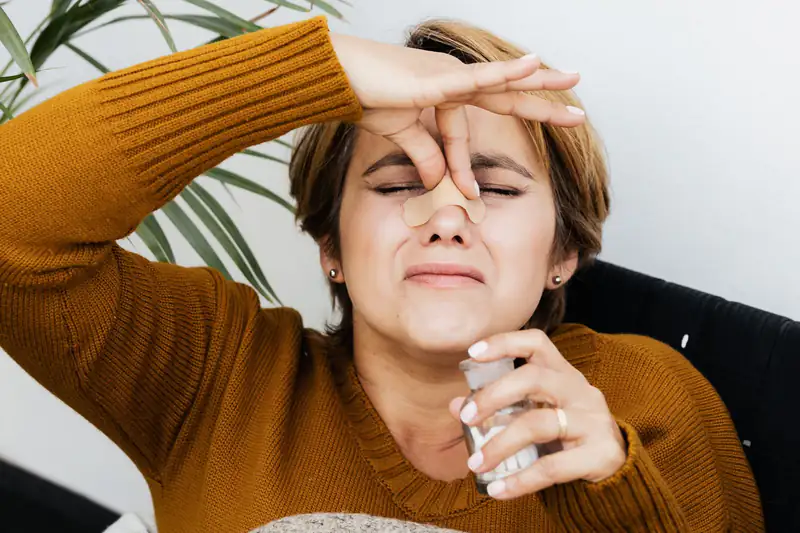 Woman pinching her nose at home after noticing a musty smell